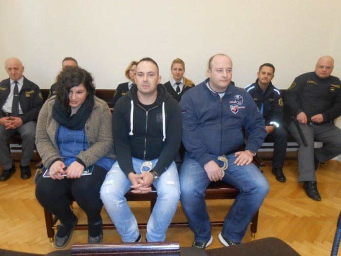 Ko na sodišče iz pripora pripeljejo glavne tri obtožence, Polono  Kukovičič, njenega partnerja Maria Urha in Roberta Žirovnika, je  razpravna dvorana takoj polna, saj vsakega od njih spremljata dva  pravosodna policista oz. pravosodni policistki.