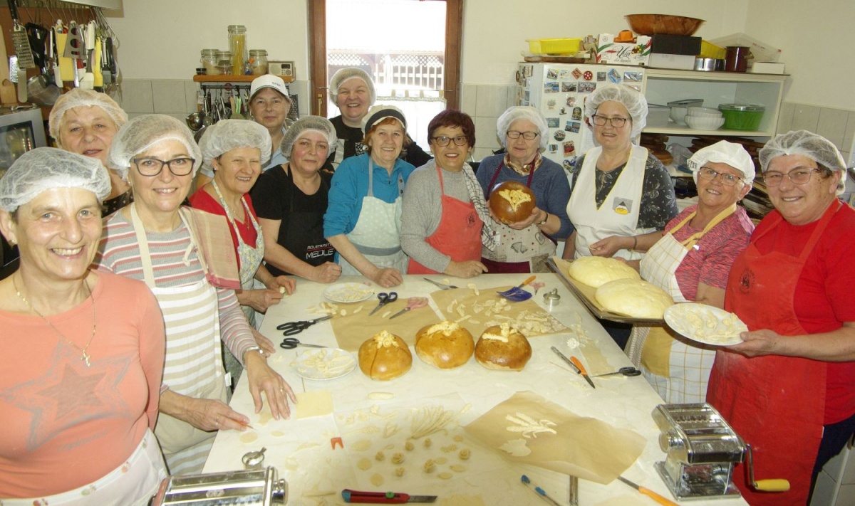 Nasmejane članice Društva kmetic Šentjernej na delavnici prazničnega kruha z okraski z Olgo Vene (četrta z desne).
